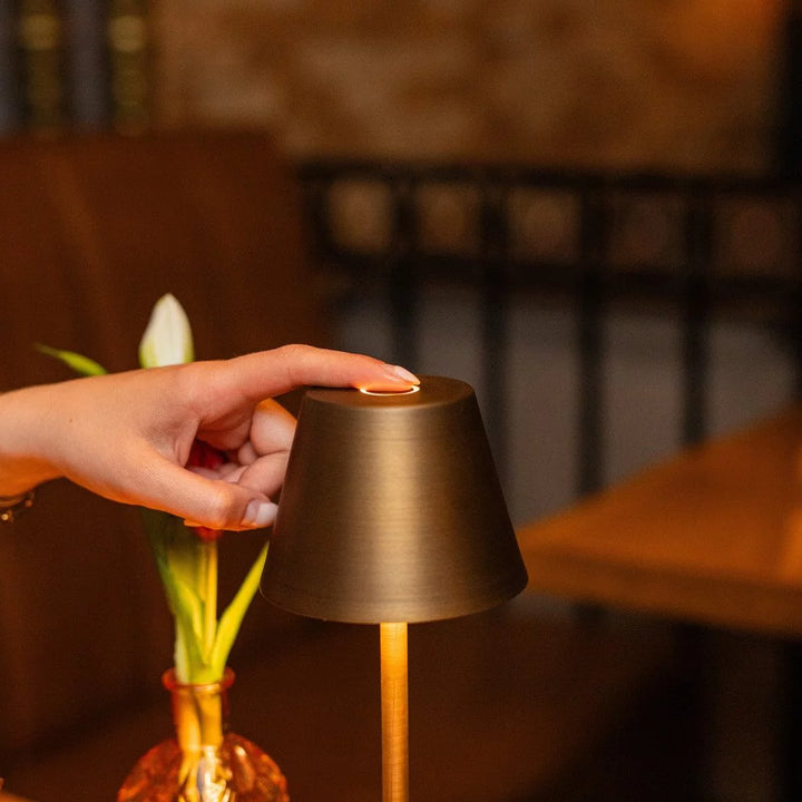 Hand berührt Touch-Sensor der Tischleuchte im warm erleuchteten Bar- und Gastrobereich
