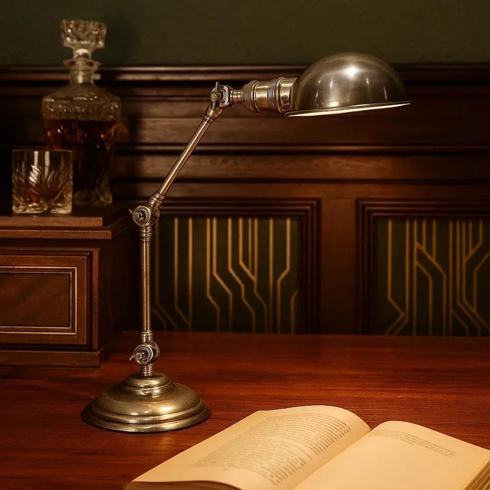 Vintage Gelenkarm-Schreibtischlampe in Antiksilber eingeschaltet über aufgeschlagenem Buch auf dunklem Holztisch