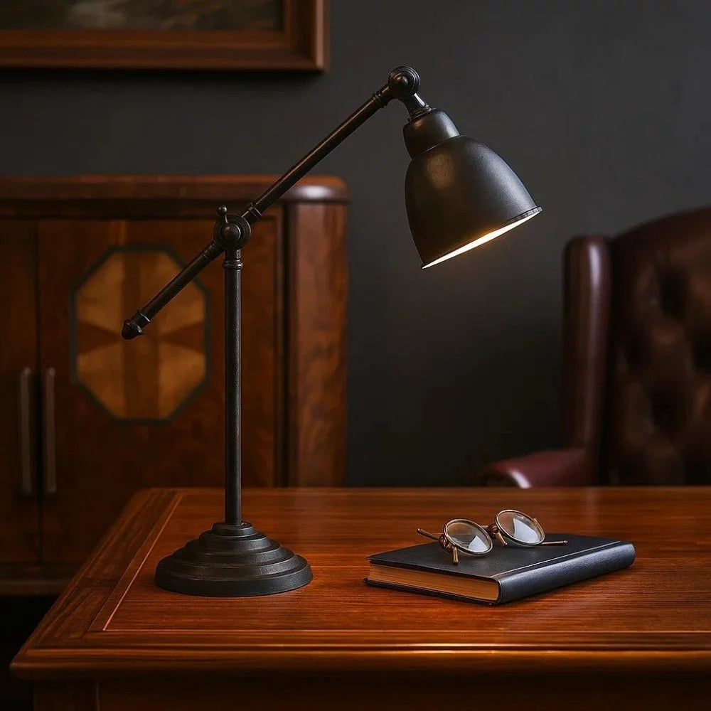 Vintage Glockenschirm-Spotlampe in Antikschwarz eingeschaltet über Buch und Brille auf edlem Holzschreibtisch