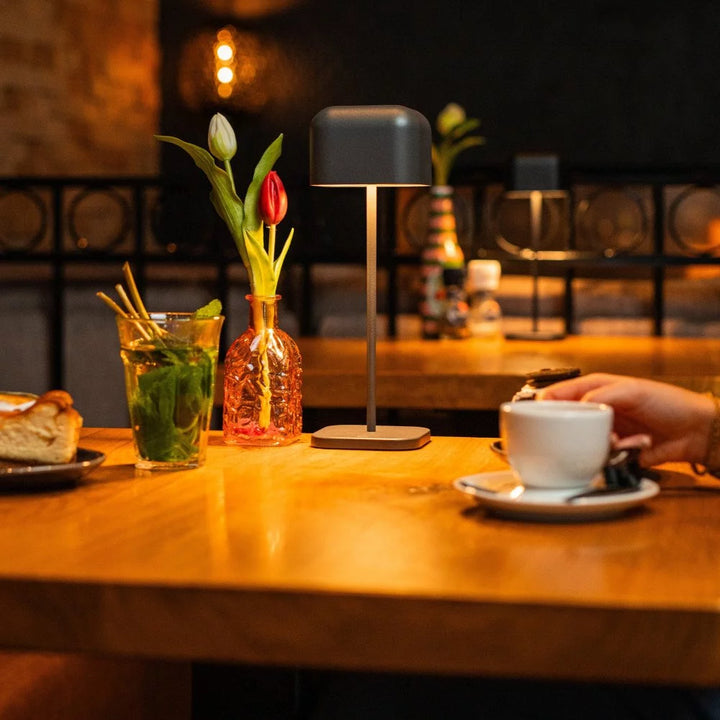 Akkulampe in Dunkelgrau spendet angenehmes Licht auf dem Bistrotisch beim Kaffeeplausch