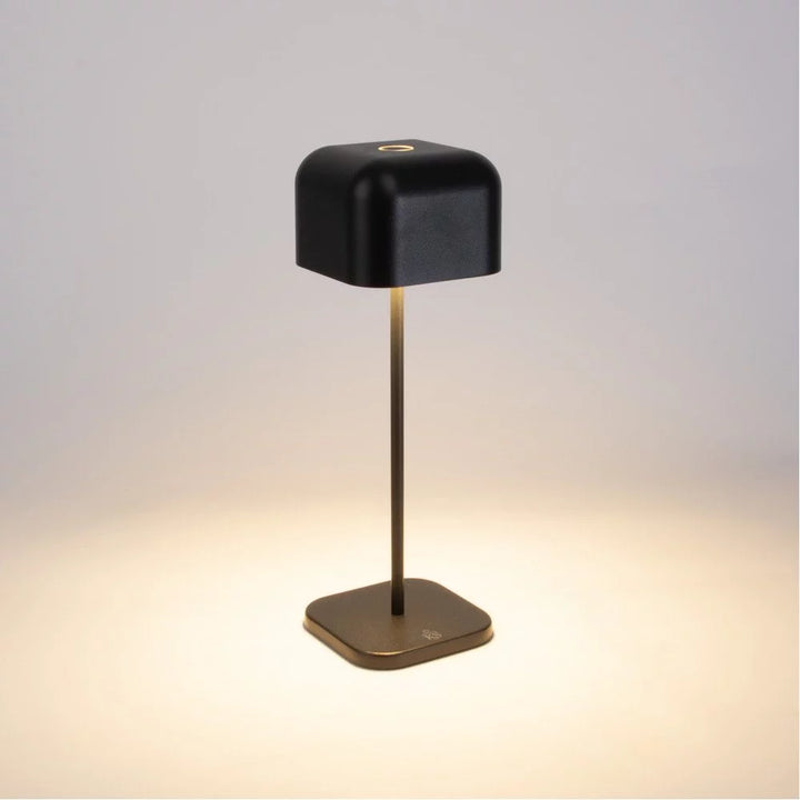 Dunkelgraue Akku Tischlampe eingeschaltet mit Touch-Sensor oben und warmem Lichtschein auf dem Sockel