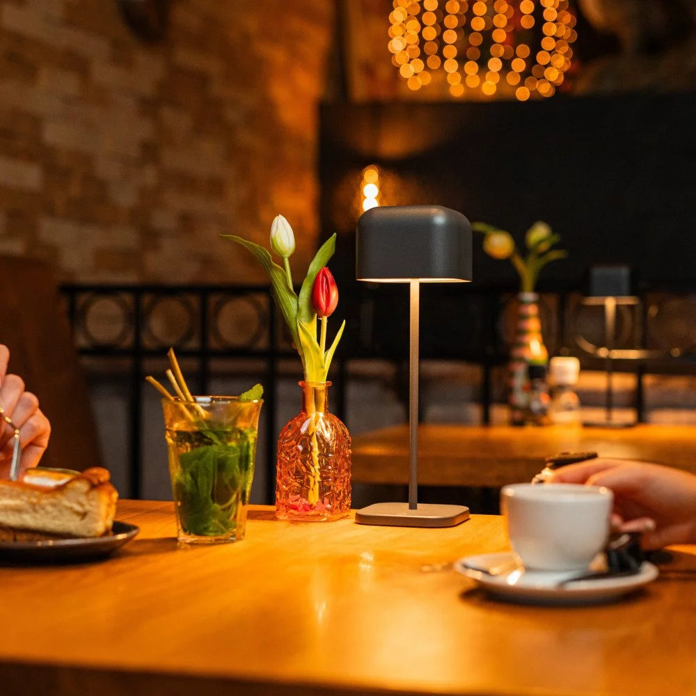 Gemütliche Tischatmosphäre im Bistro mit warmer Beleuchtung in Anthrazit und Kaffeegedeck