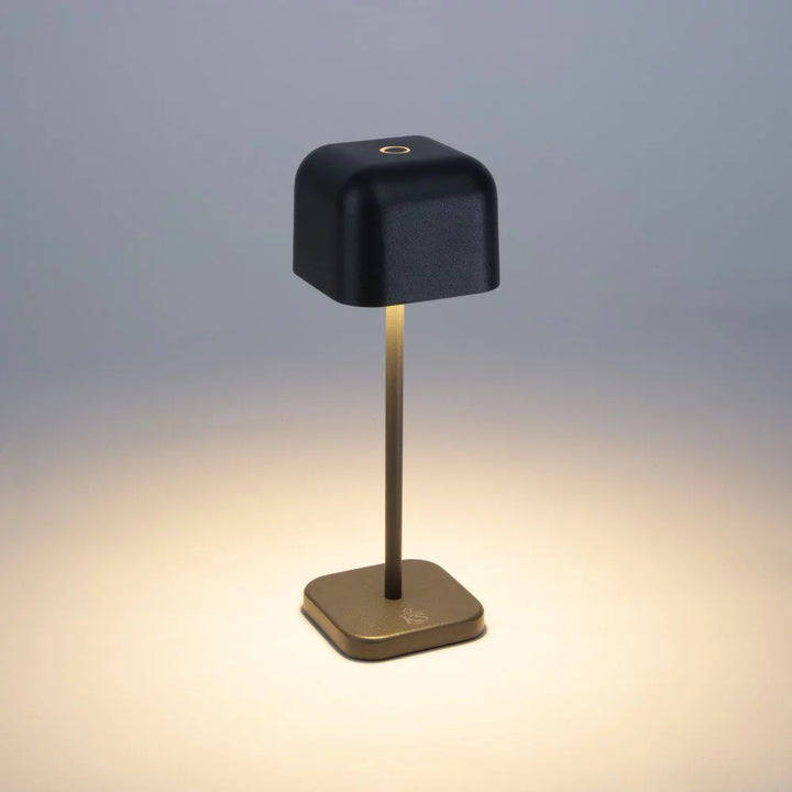 Dunkelgraue Akku Tischlampe eingeschaltet mit warmem Downlight-Kegel und Touch-Sensor auf dem Schirm