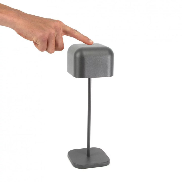 Zeigefinger bedient Touch-Dimmer auf dem Schirm der dunkelgrauen Akku Tischleuchte