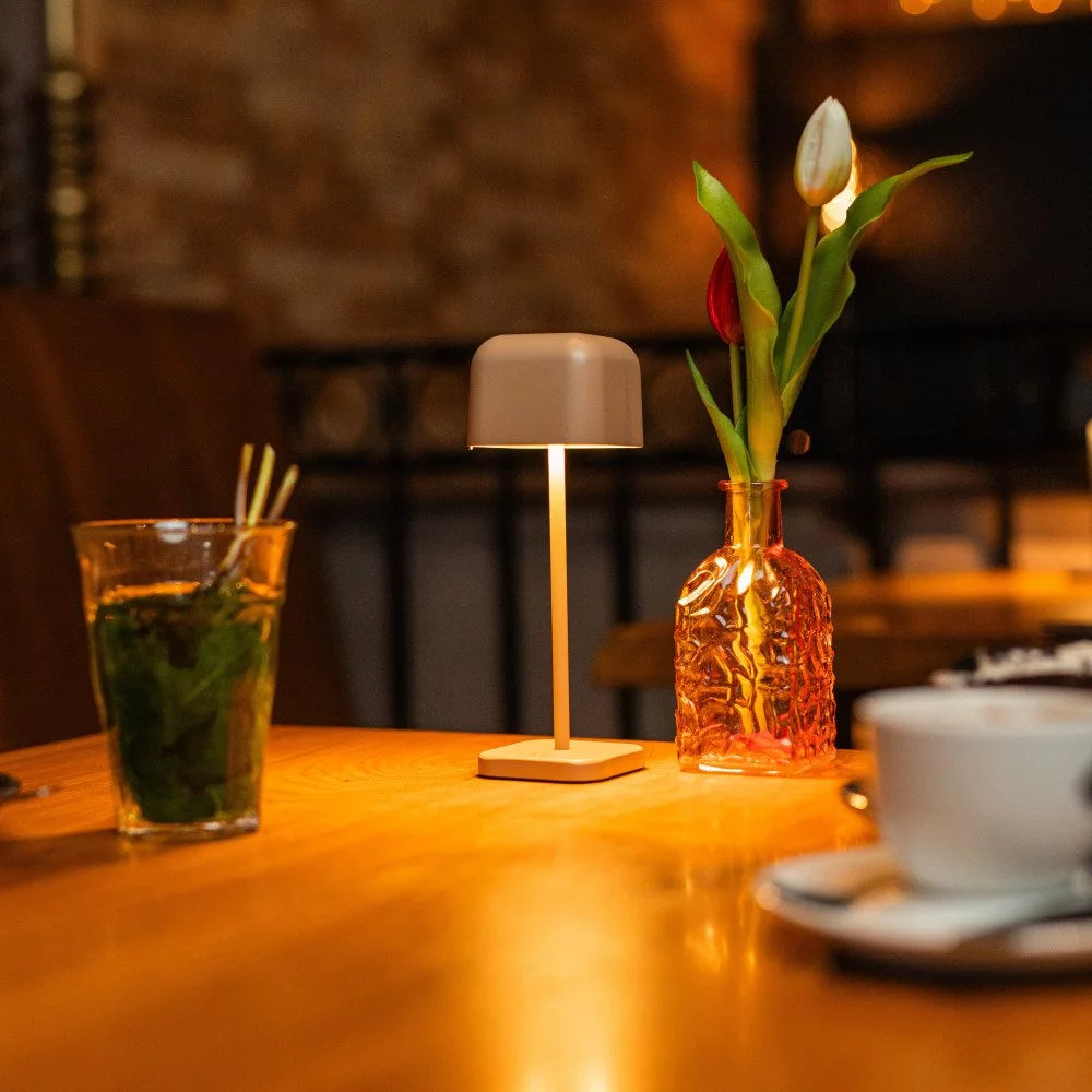 Kabellose Tischlampe Cabo Small Grau Beige im Café – warmes Stimmungslicht kompakt