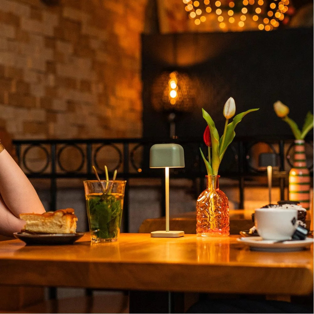 Gemütliches Café-Ambiente mit der eingeschalteten Tischleuchte, Minztee und Kaffeetasse