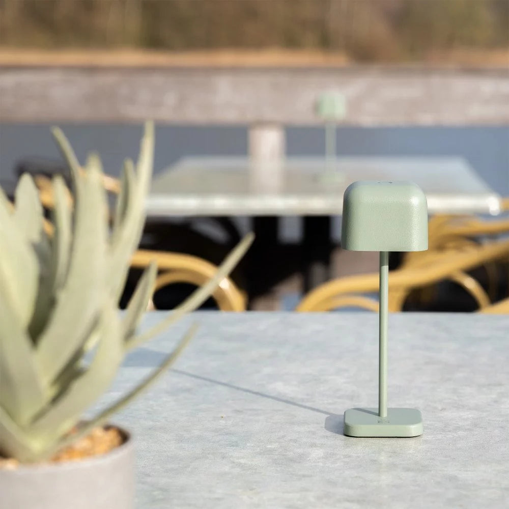 Kompakte Outdoor-Akkuleuchte auf Steintisch im Restaurant-Außenbereich am Steg