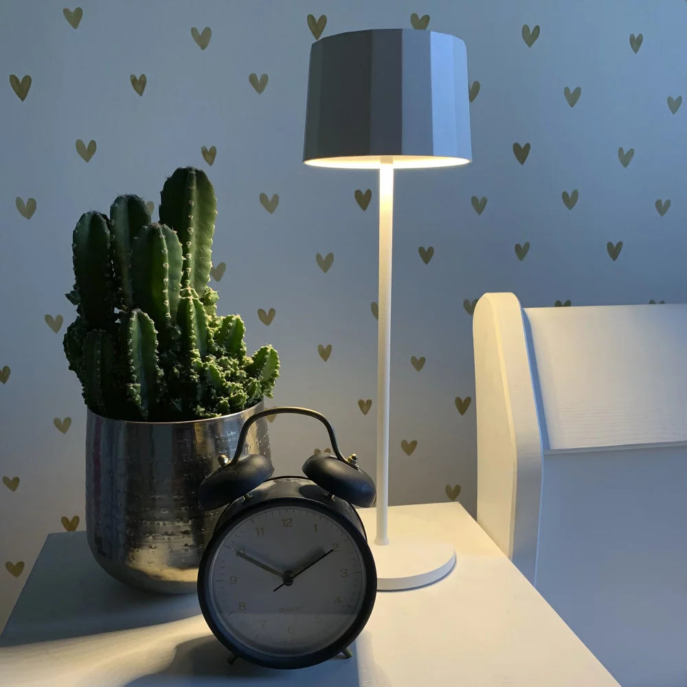 Kabellose Tischlampe Lido Corten auf weißem Nachttisch mit Wecker – warmweißes Schlafzimmerlicht