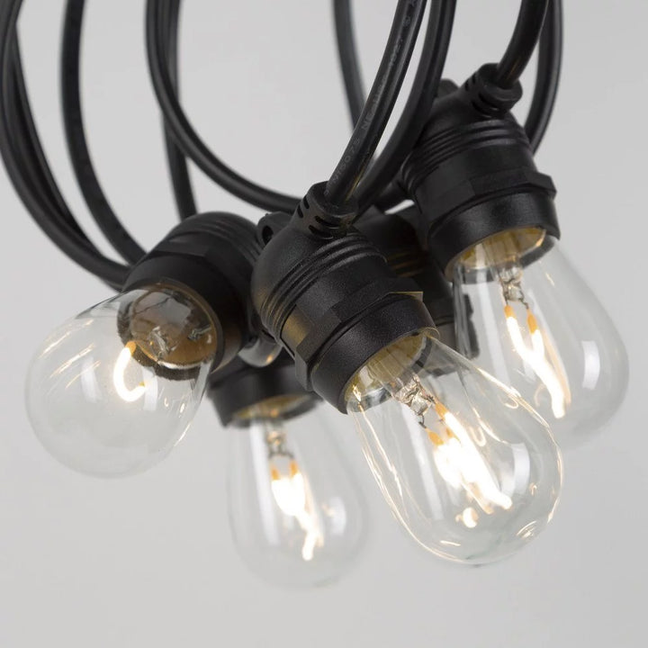 Nahaufnahme der eingeschalteten Lampen in wetterfesten E27-Gummifassungen mit integrierter Aufhängeöse an schwarzem Kabel