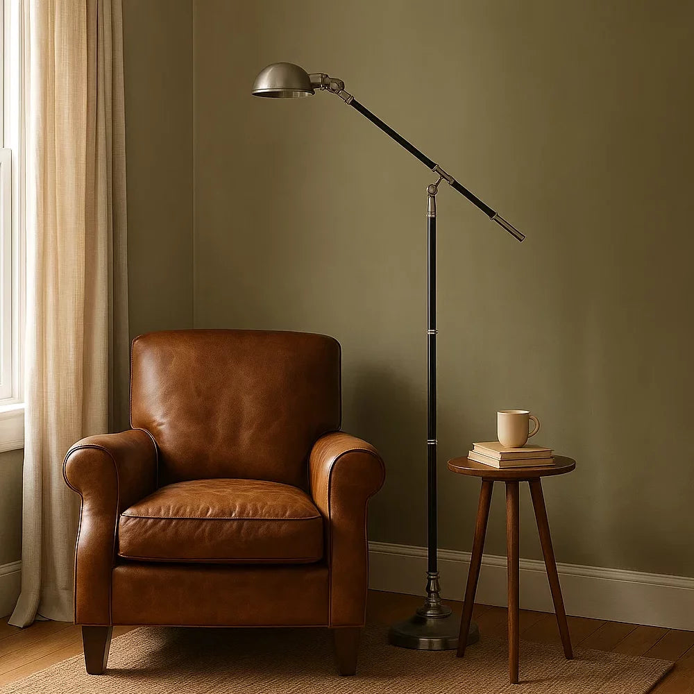 Eingeschaltete Stehlampe in Bicolor-Optik Schwarz und Antiksilber neben cognacfarbenem Ledersessel und Nussbaum-Beistelltisch