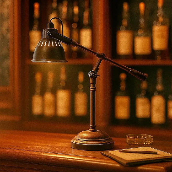 Vintage Wipparm-Schreibtischlampe in Antikschwarz leuchtet über Notizbuch vor beleuchtetem Whisky-Regal